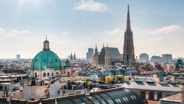 Panoramic view of Vienna in sunshine with a view of St. Stephens Cathedral and St. Peters Church with its distinctive domed roof.