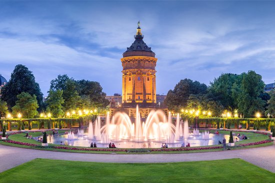 Stadtansicht von Mannheim mit dem markanten Wasserturm im Vordergrund, umgeben von grünen Parkanlagen und historischen Gebäuden.