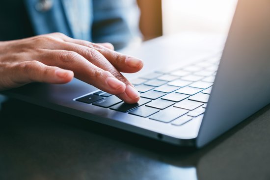 Eine Frau tippt auf einer Laptop-Tastatur