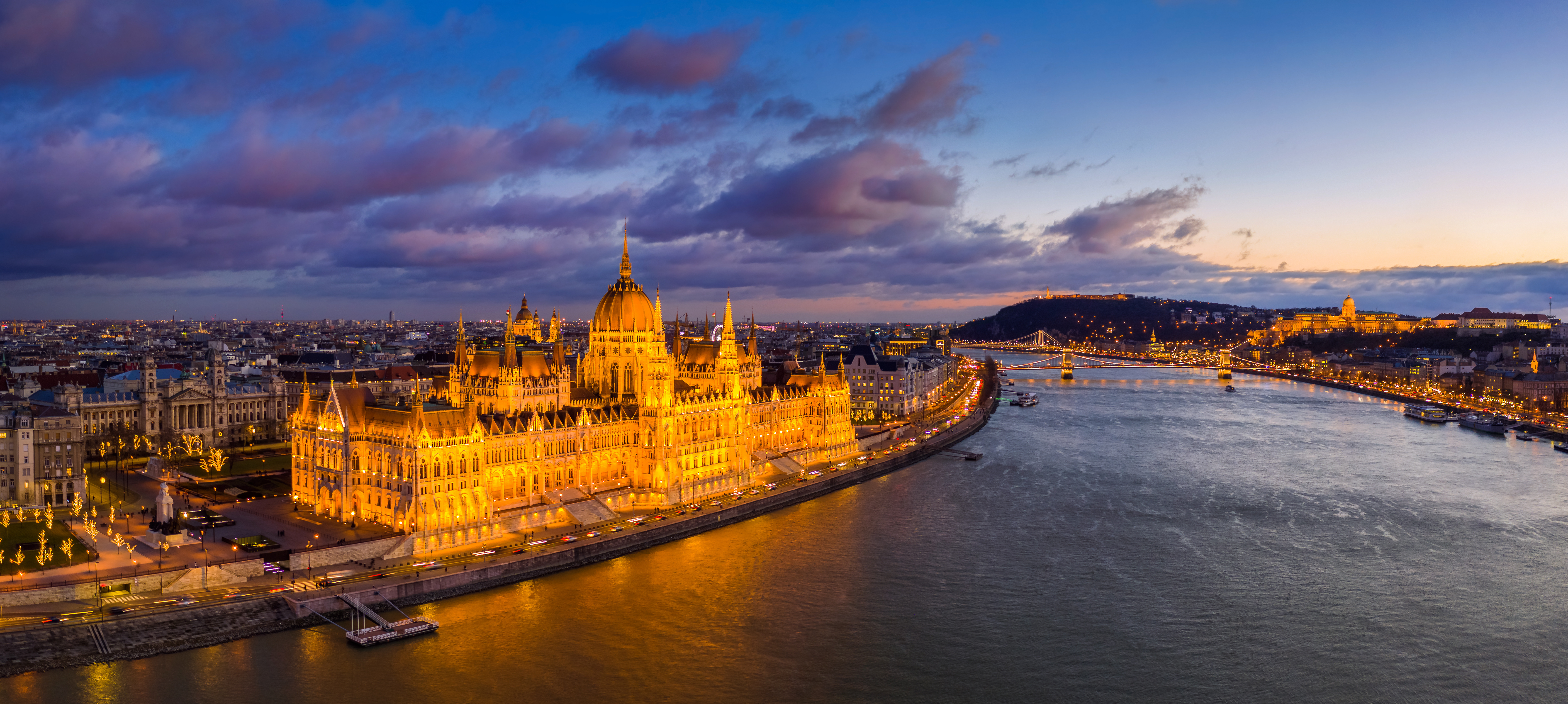 Panorama von Budapest bei Nacht, mit der Kettenbrücke und dem beleuchteten Parlamentsgebäude am Ufer der Donau.